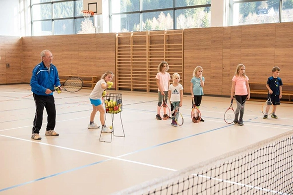 Eine Gruppe Kinder mit ihrem Tennislehrer beim Tenniskurs